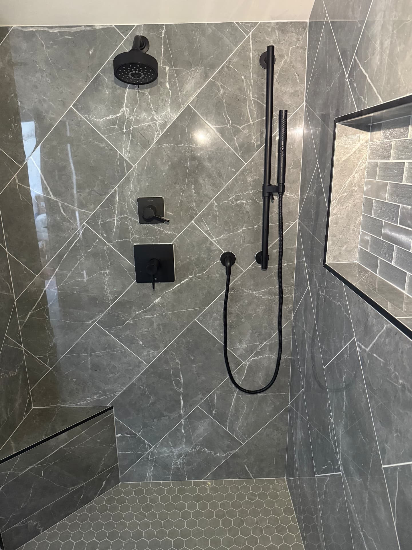 Finished shower with dark fixtures and gray tile installed by Klean Plumbing