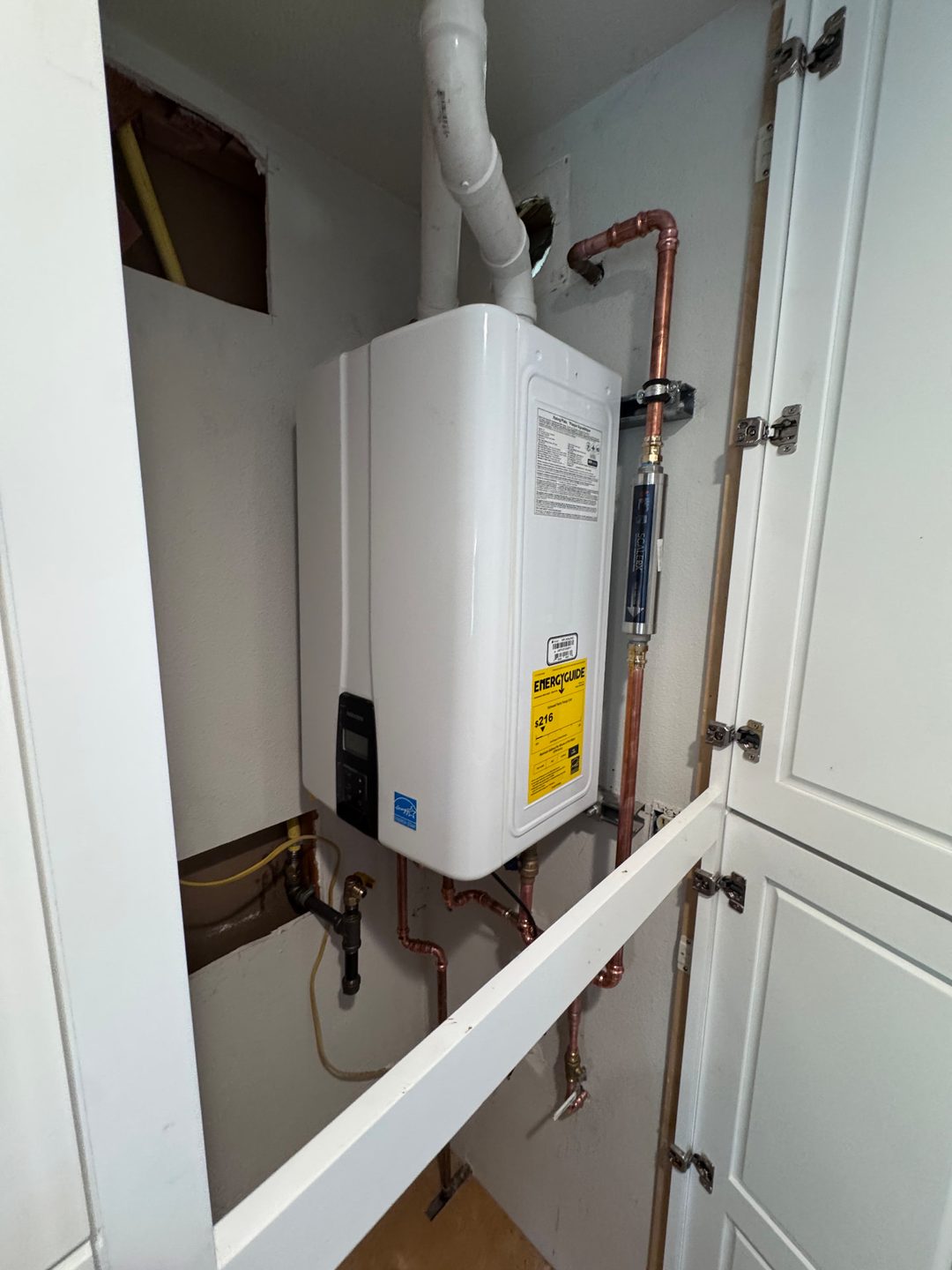 Wall-mounted tankless water heater with copper lines and an in-line water filter