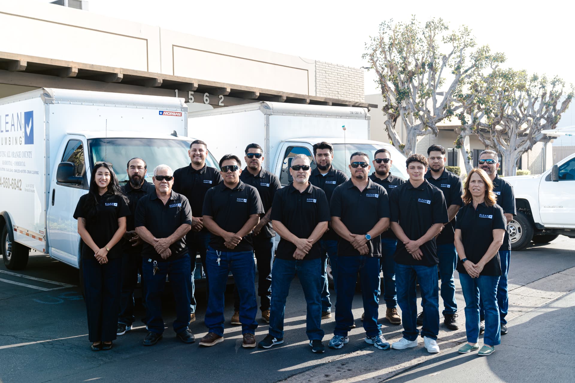 The Klean Plumbing team standing together in front of company trucks